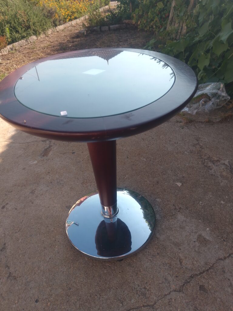 il s'agit d'une table d'appoint ronde, en bois, pied chromé et verre sur le dessus