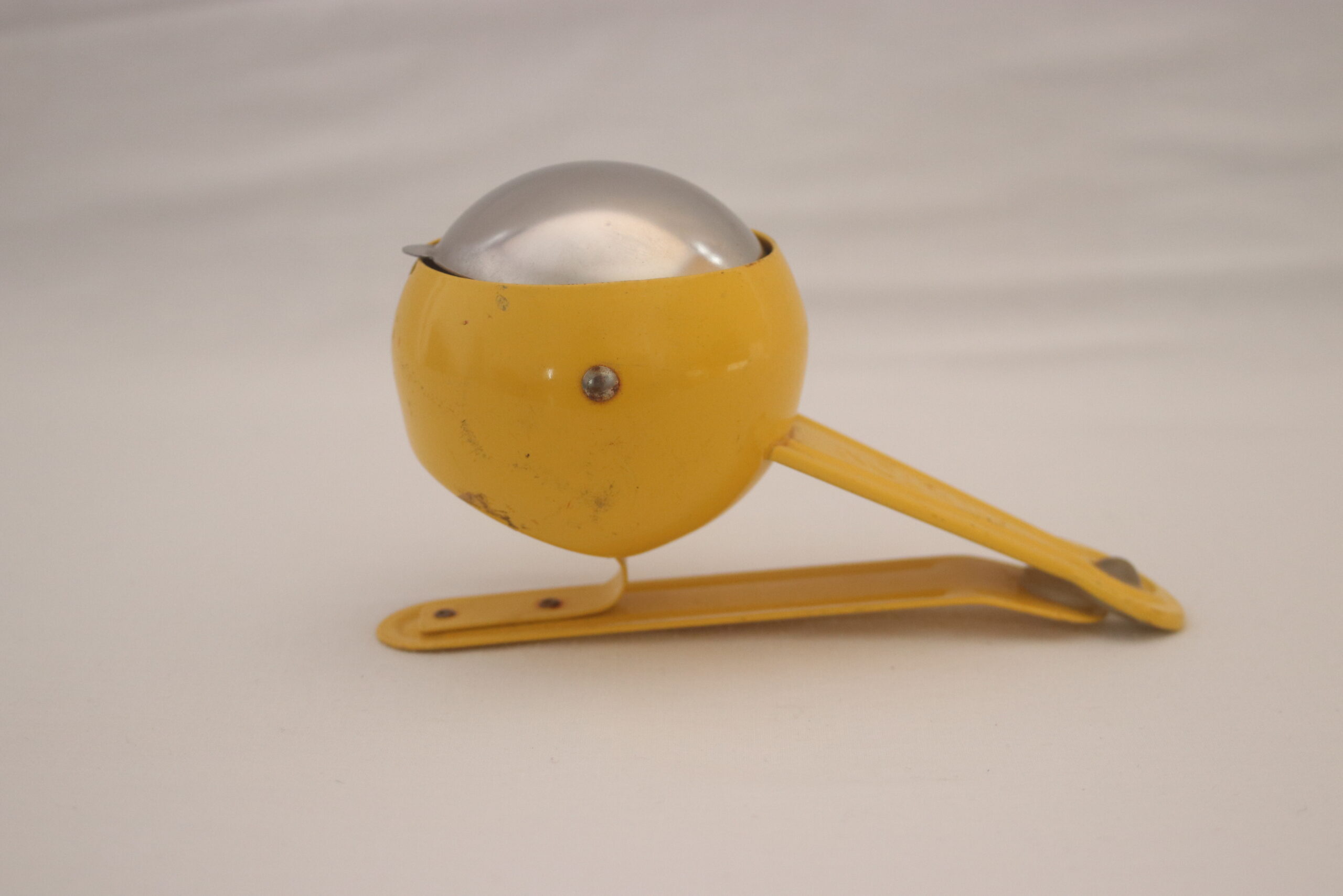 ce cendrier de table est jaune, en fer et possede une pince